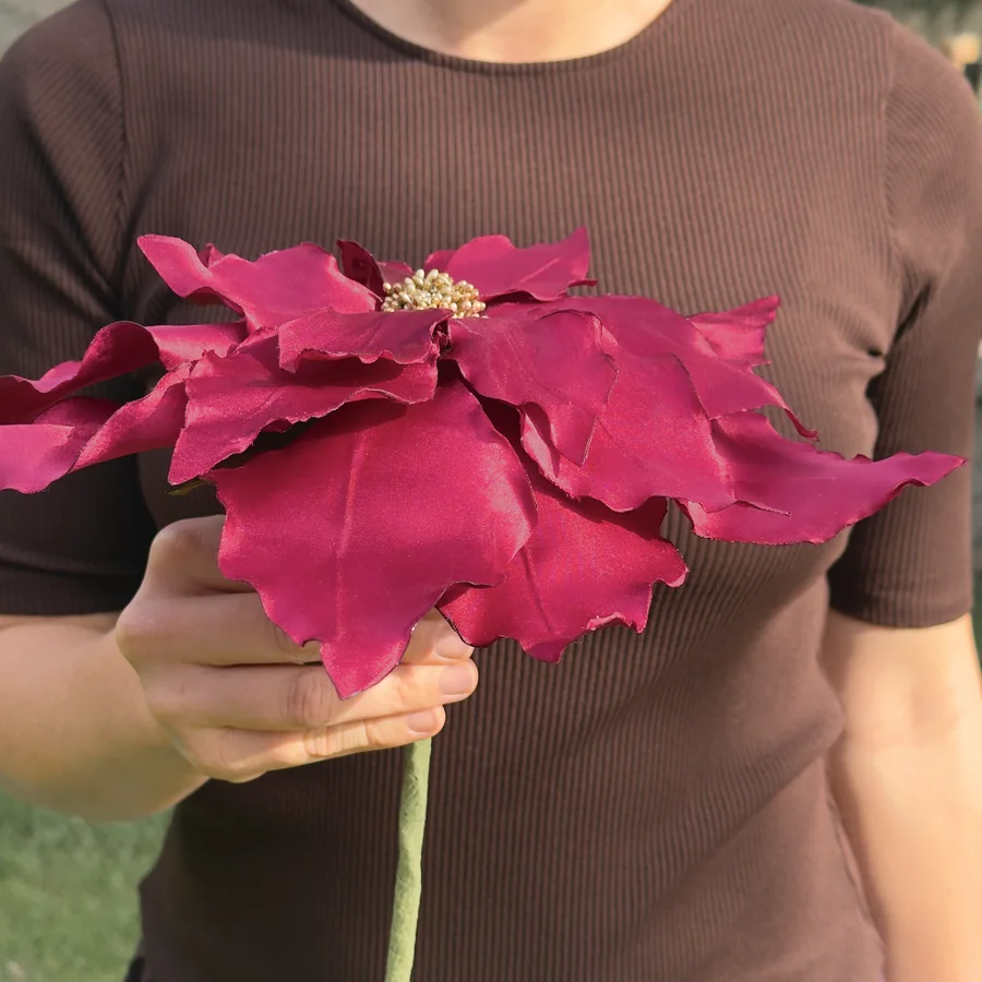 A finished satin poinsettia held by its stem