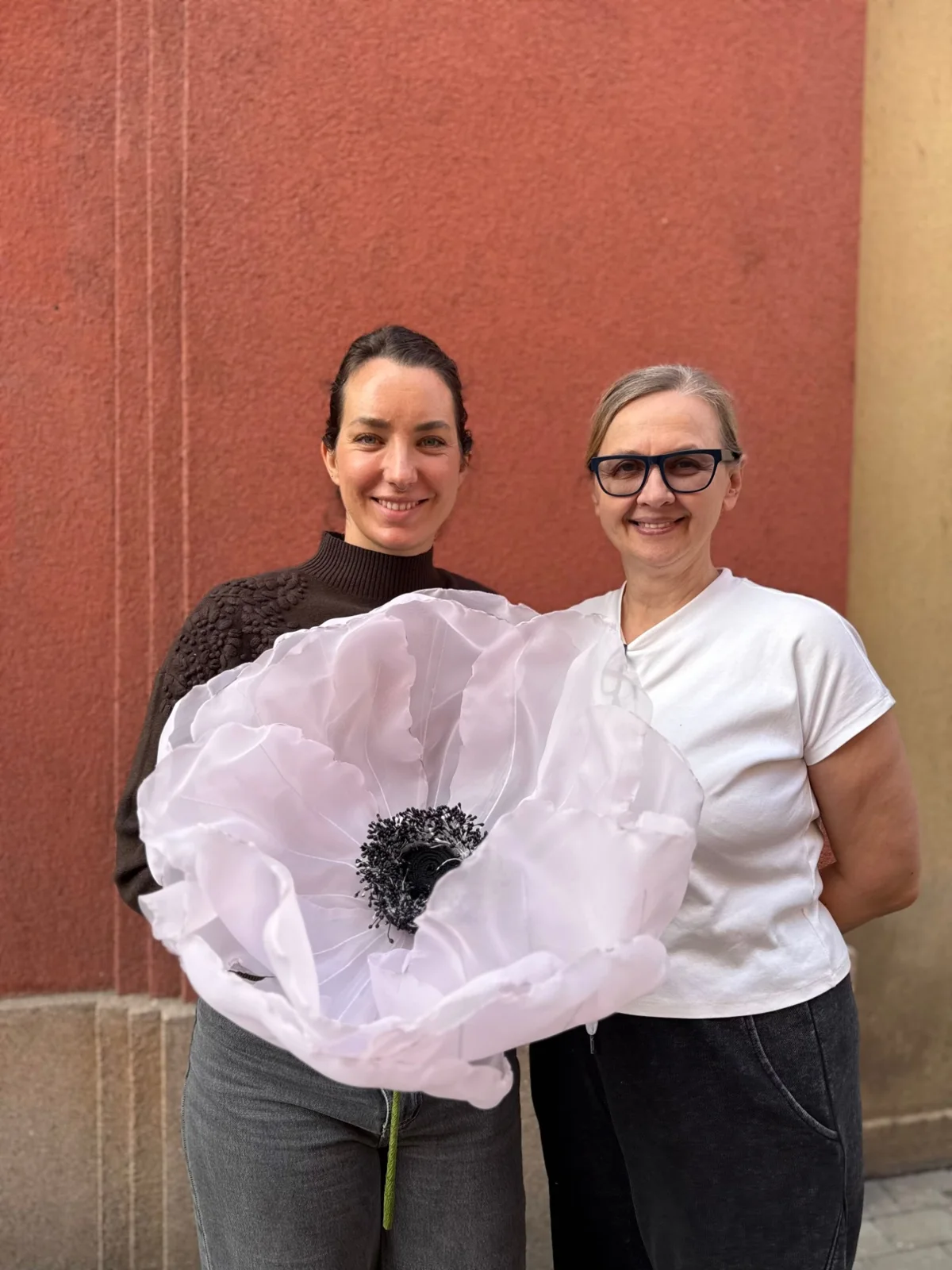 Tereza and her mother-in-law outdoors, holding a giant white organza poppy