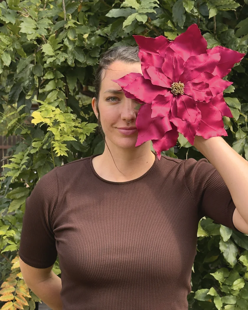 Tereza holding a satin poinsettia she made up to her face